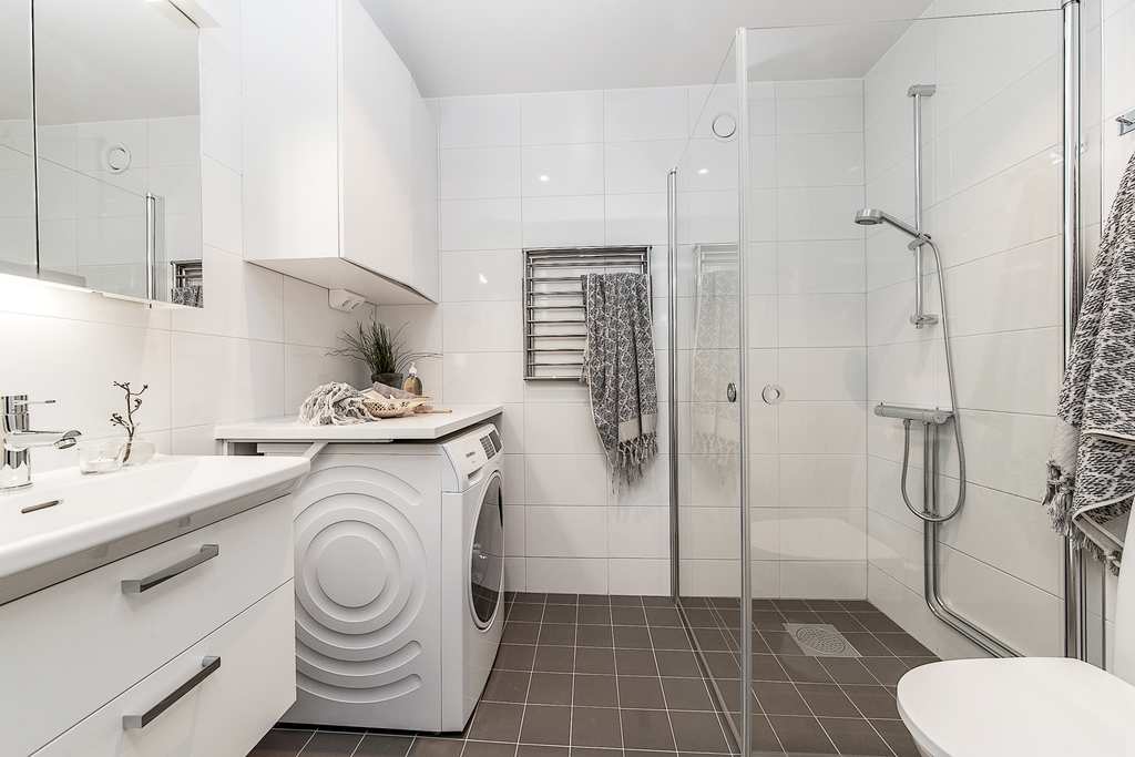 Helkaklat badrum med tvättmaskin och vikbara duschväggar